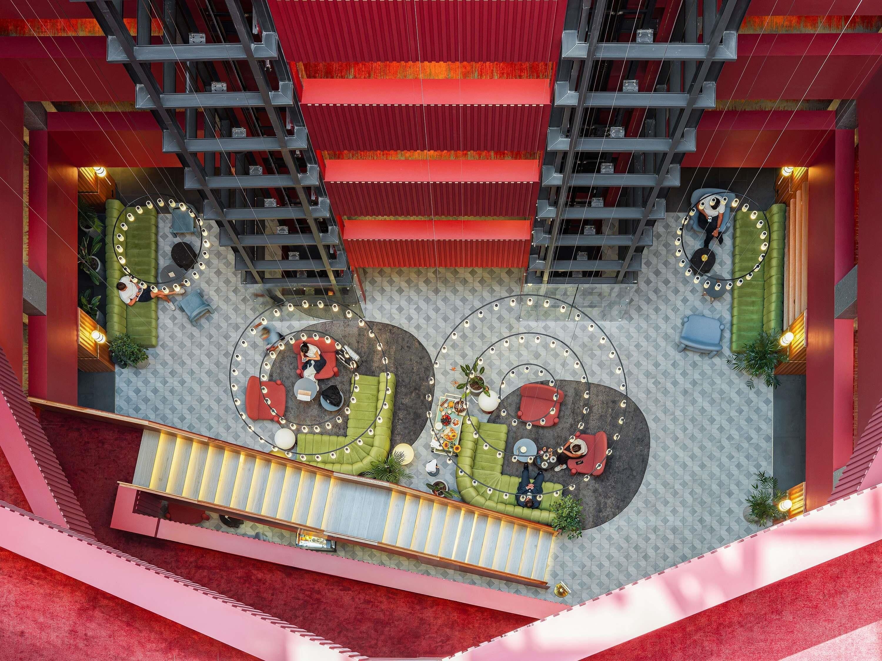 Um átrio amplo em vários níveis, com áreas de estar circulares, escadas e uma escadaria central.
