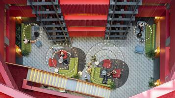 Um átrio amplo em vários níveis, com áreas de estar circulares, escadas e uma escadaria central.