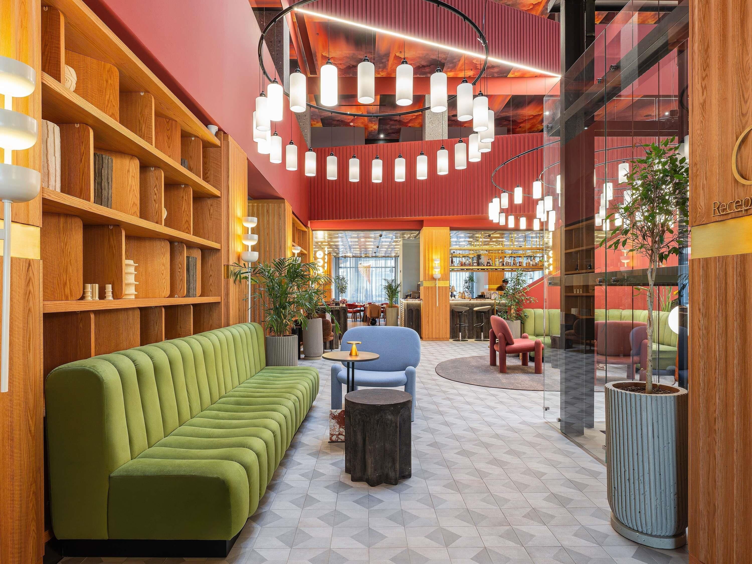 Un interior moderno con un sofá verde, una zona de bar y un mostrador de recepción.