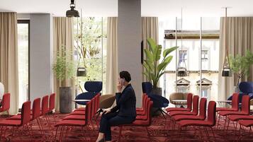 A hotel lobby with a seating area, a large plant, and a view of a building outside.
