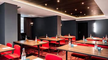 A conference room with multiple tables and red chairs, equipped with water bottles and glasses.