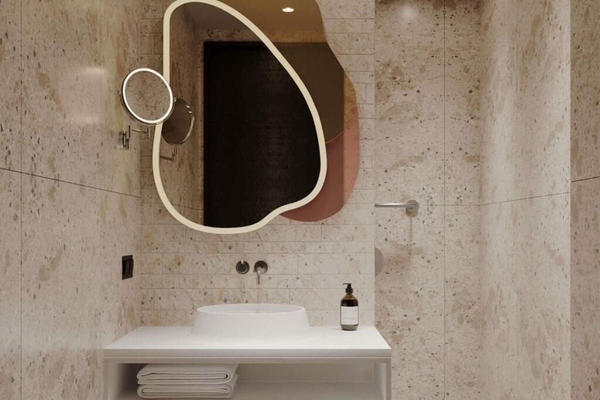 A modern bathroom with a white sink, a large mirror, and a towel rack.