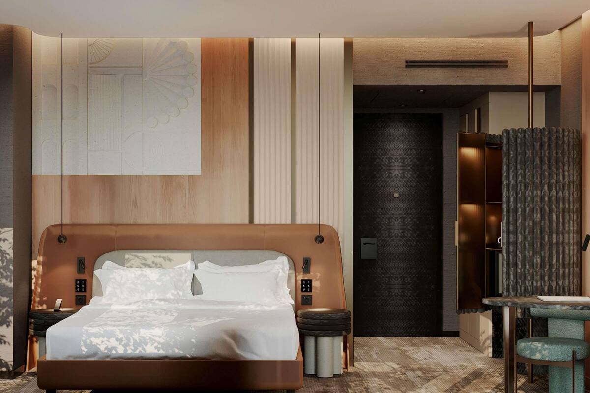 A modern hotel room with a large bed, a small seating area, and a dark textured wall.