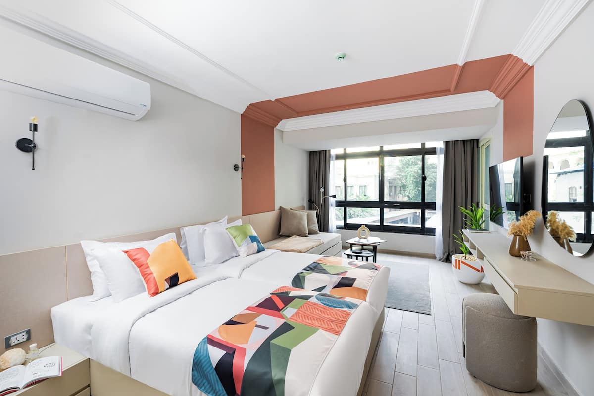 Une chambre d’hôtel moderne avec un grand lit, un canapé, un bureau et une grande fenêtre.