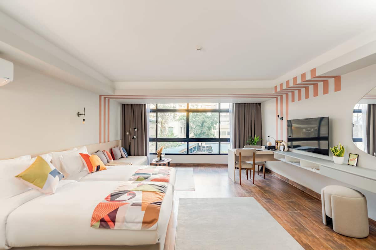 Une chambre d’hôtel moderne, dotée d’un grand lit, d’un bureau, d’une télévision et offrant une vue sur l’extérieur.