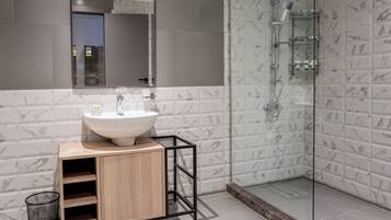 A modern bathroom with a marble-tiled shower, a wooden vanity with a sink, and a large mirror.