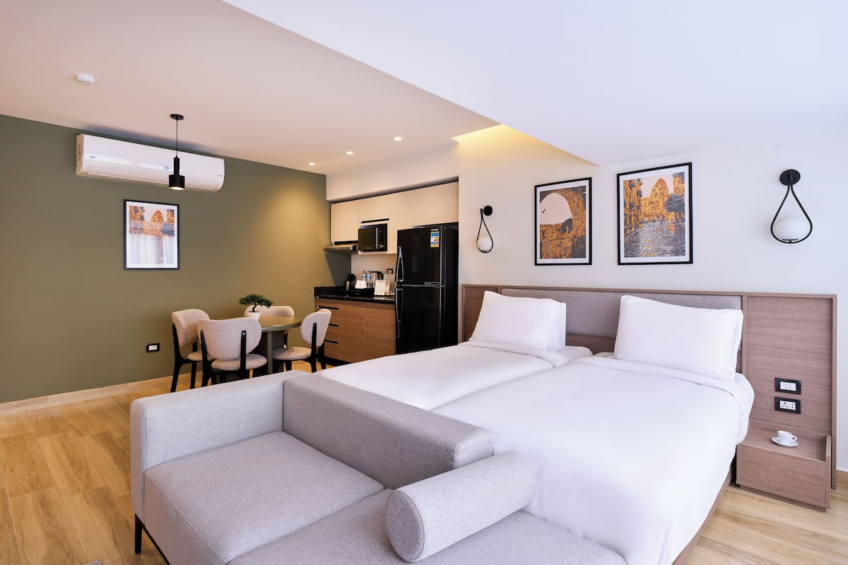 Une chambre d’hôtel moderne dotée d’un grand lit, d’un canapé, d’un coin repas et d’une cuisine.