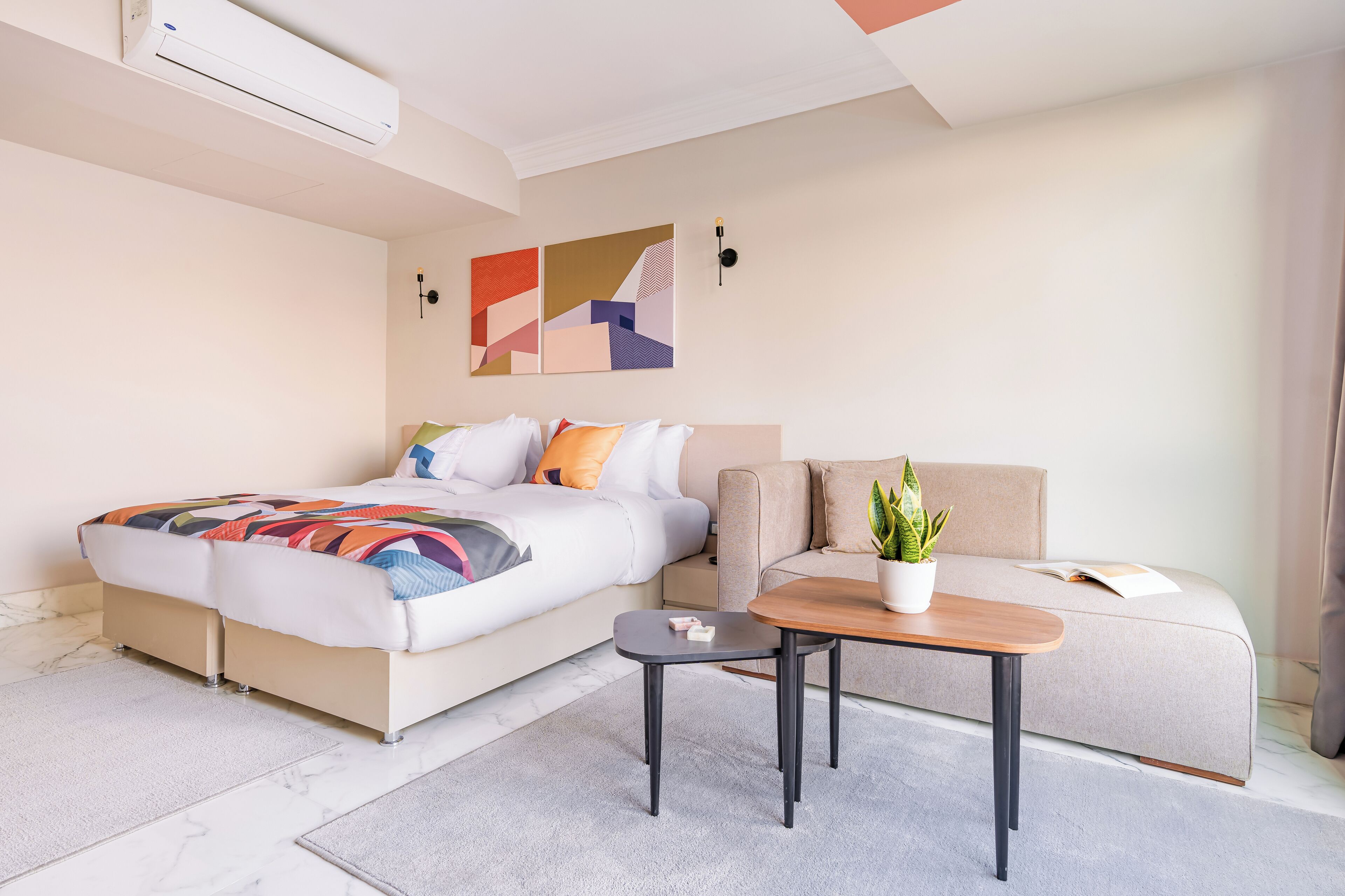 Ein modernes Hotelzimmer mit Bett, Sofa, kleinem Tisch und einer Topfpflanze.