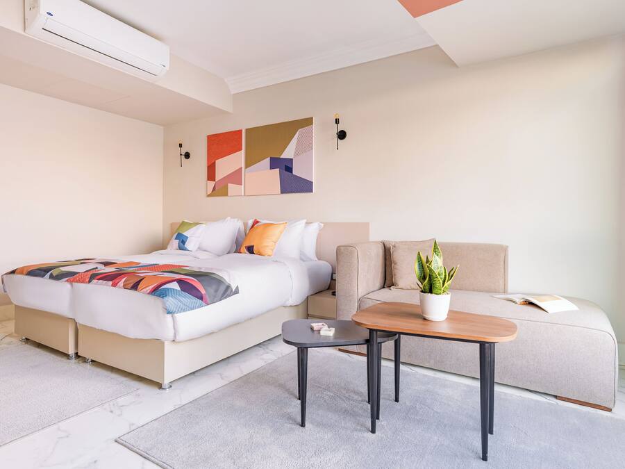 Ein modernes Hotelzimmer mit Bett, Sofa, kleinem Tisch und einer Topfpflanze.