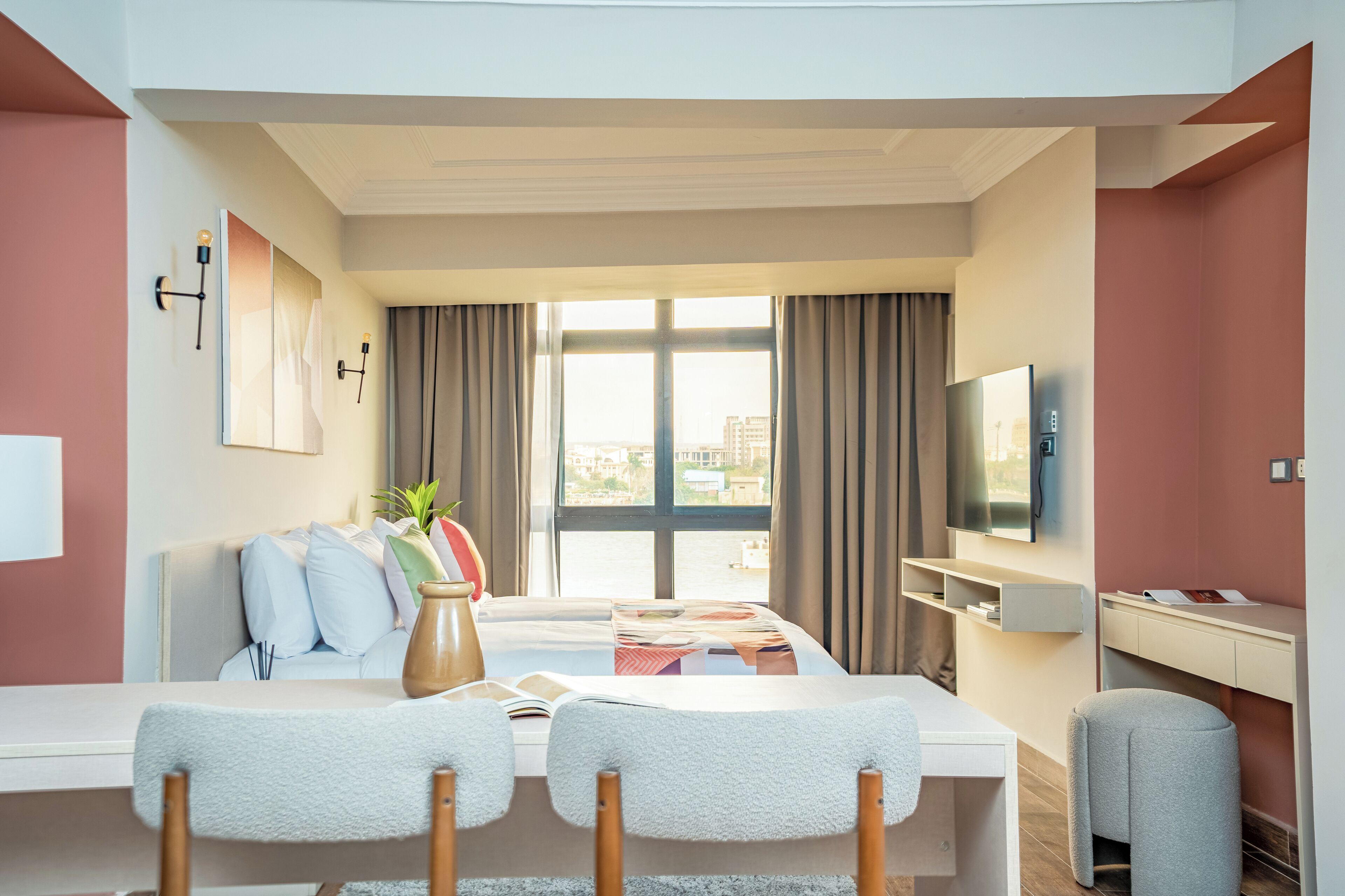 Una habitación de hotel moderna con una cama grande, un escritorio, un televisor y vistas a la ciudad.