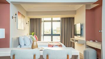 Una habitación de hotel moderna con una cama grande, un escritorio, un televisor y vistas a la ciudad.