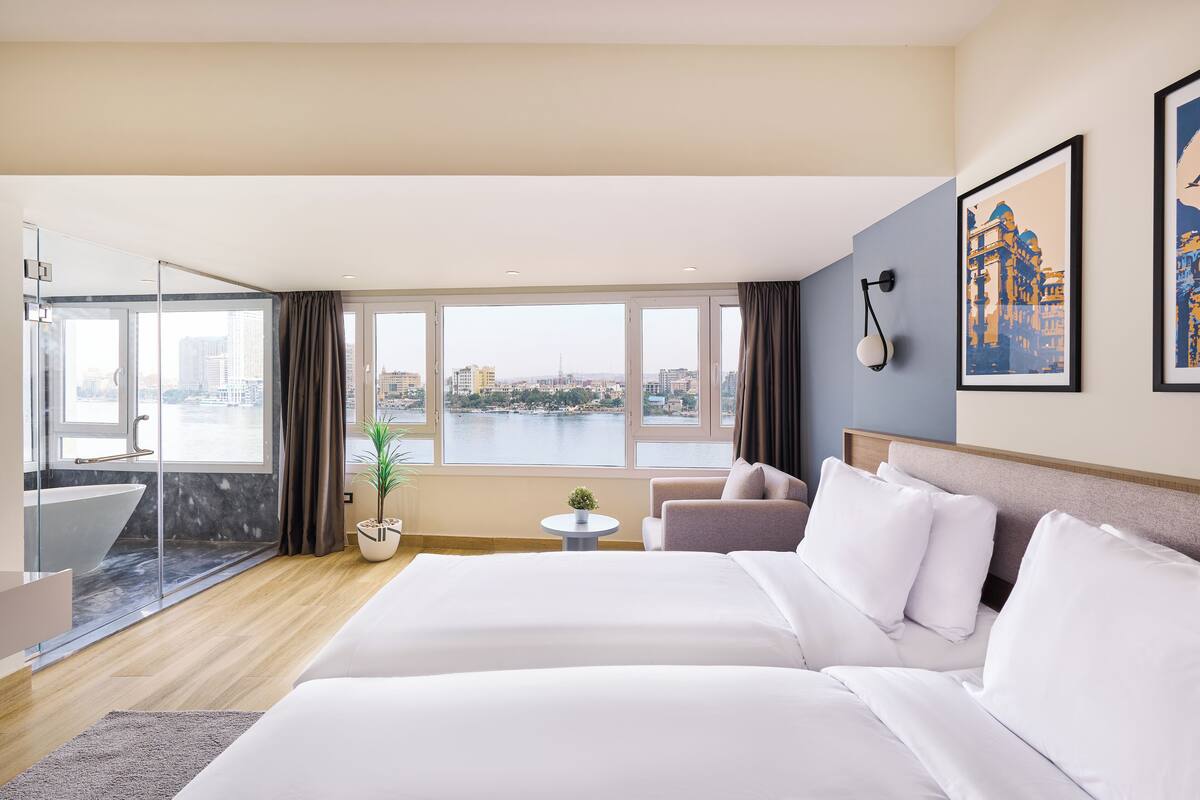 Une chambre d’hôtel avec un grand lit, un canapé, une petite table et une vue sur la ville.
