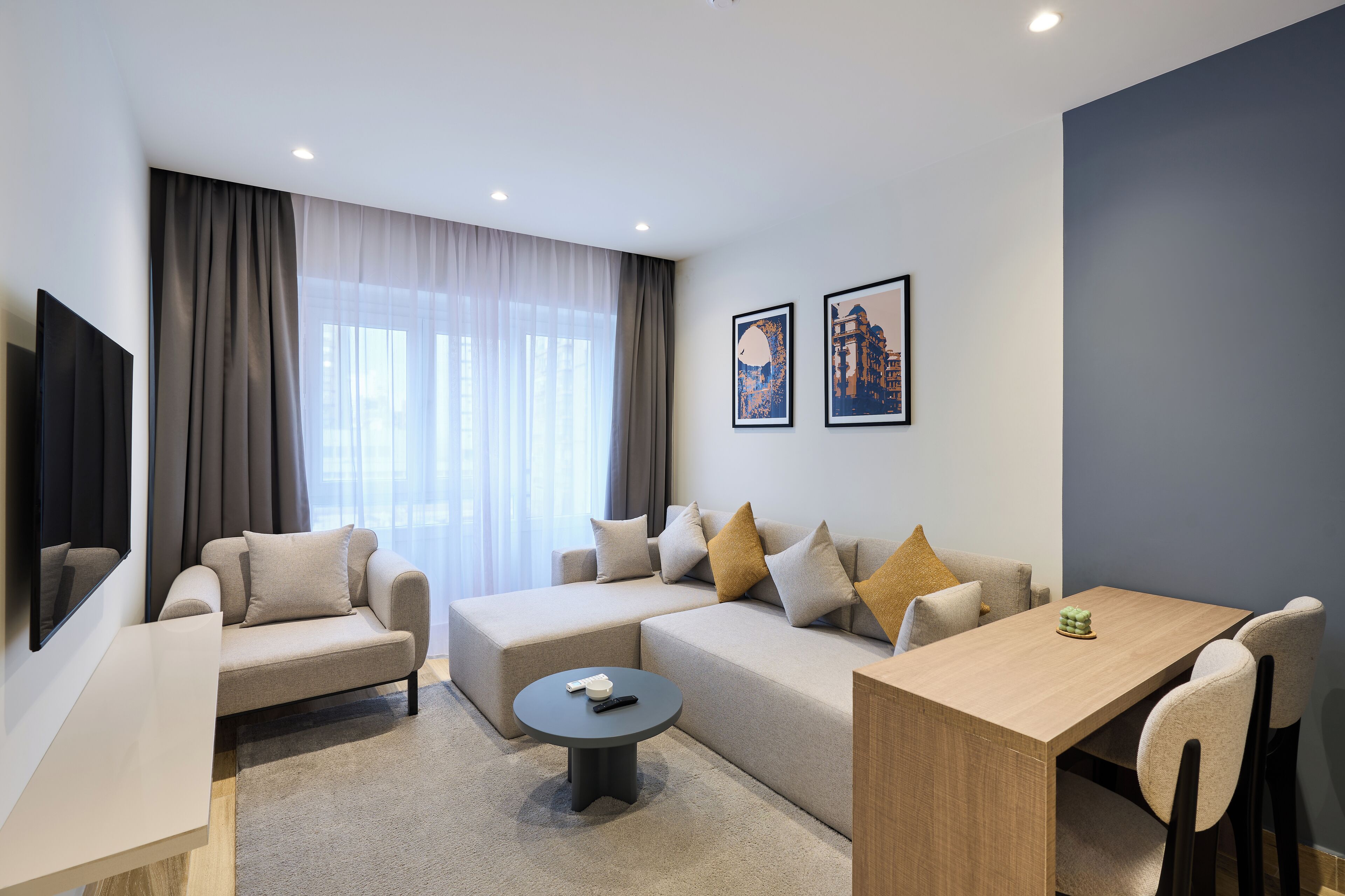 Un salon moderne comprenant un canapé, une table basse, une table à manger et un téléviseur fixé au mur.