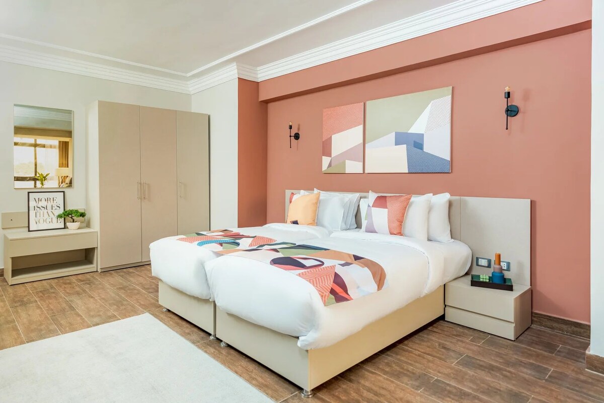 A bedroom with a bed, bedside tables, a wardrobe, a mirror, and artwork on the wall.