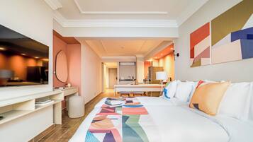 A hotel room with a bed, a desk, a TV, and a bathroom visible through an open door.