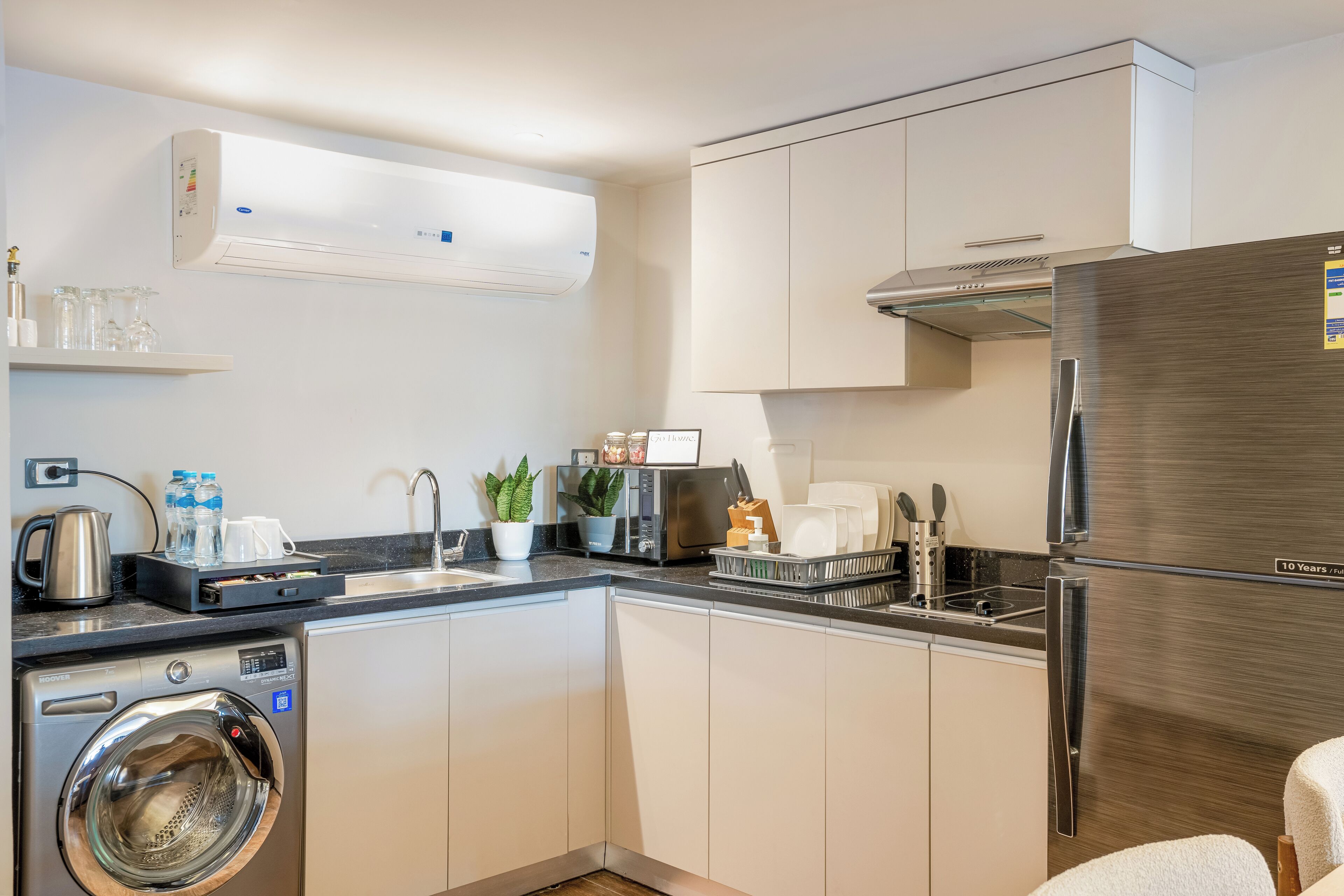 Una cocina compacta con lavadora, refrigerador y microondas.
