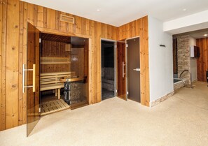 A wooden interior with a sauna, a shower area, and a stone wall. - Keilberg Resort klínovec (Loucna Pod Klinovcem)