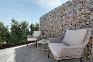 Une terrasse dotée de meubles en osier et d’un mur en pierre.