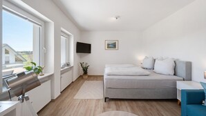 Une chambre à coucher moderne avec un lit, une télévision, une fenêtre et une vue sur l’extérieur.