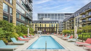 Une piscine sur le toit, dotée de chaises longues, avec un bâtiment moderne en arrière-plan.