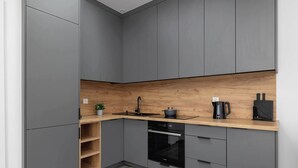 A modern kitchen with grey cabinets, a wooden countertop, a built-in oven, and a sink. - Functional Studio | Air Conditioning | Close to Train Station (Katowice)