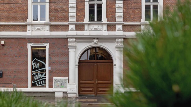 A brick building with a large wooden door and a smaller door with a sign. - Functional Studio | Air Conditioning | Close to Train Station (Katowice)