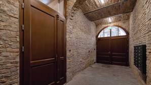 A narrow corridor with stone walls and wooden doors, leading to a room with a view through an arched window. - Functional Studio | Air Conditioning | Close to Train Station (Katowice)
