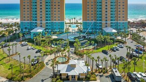 Un hotel con due edifici alti, una piscina centrale e vista sulla spiaggia.