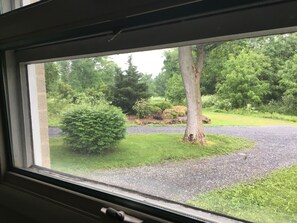 A window view of a green landscape with trees and a gravel path. - Private One Bedroom Apartment on a Golf Course (Dillsburg)