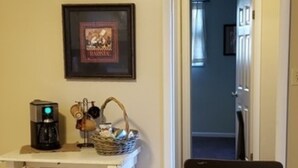 A dining area with a granite table, two chairs, a coffee maker, and a framed picture on the wall.