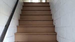 A staircase with beige steps and white brick walls, leading to a door at the top.