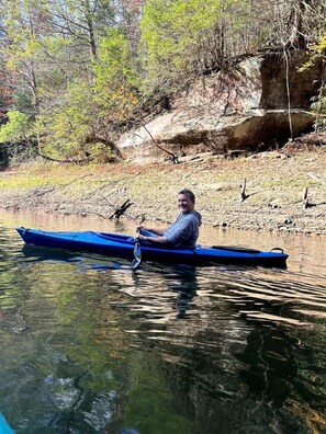 Una persona en un kayak azul en un río tranquilo.