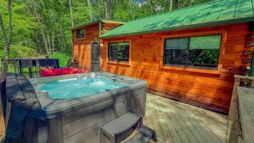 A wooden cabin with a hot tub and deck.