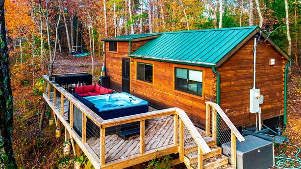 A cabin with a hot tub, deck, and a small attached building.