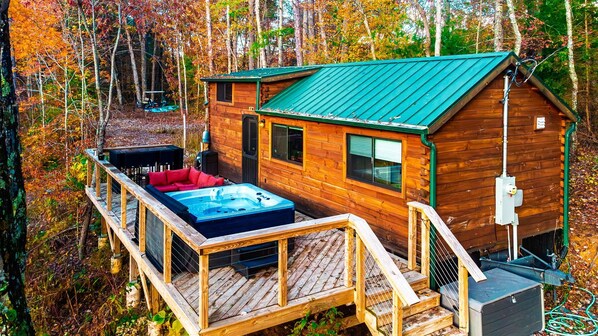 A cabin with a hot tub, deck, and a small attached building.