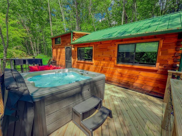 A wooden cabin with a hot tub and deck.