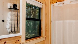 A wooden cabin bathroom with a white sink, toilet, and shower curtain.