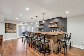Une cuisine moderne dotée d’un îlot central, de tabourets de bar, de luminaires suspendus et d’un meuble à vin intégré.