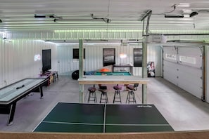 Une pièce équipée d’une table de billard, de tabourets de bar, d’une table de jeux et d’une table de snooker.
