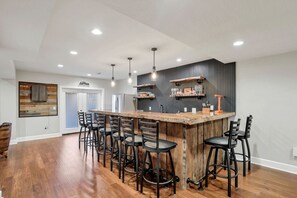 A modern kitchen with a central island, bar stools, pendant lighting, and a built-in wine rack.