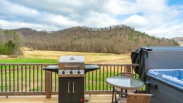 Eine Terrasse mit tragbarem Grill, Whirlpool und Korbstühlen.