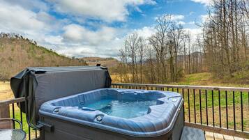 Un jacuzzi en una terraza con vistas a árboles y colinas.