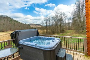 Un bain à remous sur une terrasse, avec vue sur une colline boisée.