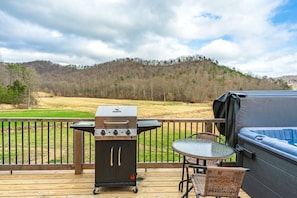 Una terraza con una parrilla portátil, un jacuzzi y sillones de mimbre.