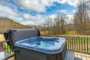Un bain à remous sur une terrasse, avec vue sur les arbres et les collines.