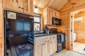 Une cuisine de taille réduite, dotée de meubles en bois, d’un réfrigérateur en acier inoxydable, d’un four à micro-ondes et d’une cuisinière.