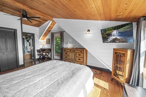 A bedroom with a large bed, wooden ceiling, a TV on the wall, and a view of a waterfall. - Heavenly Mountain VIew, Hot Tub, Fire Pit (Blue Ridge)