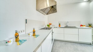 A modern kitchen with white cabinetry, a stainless steel range hood, a built-in sink, and a countertop with a bottle of beer, a mug, and a fruit bowl. - Modern house Menut in Sa Pobla with jacuzzi (Sa Pobla)