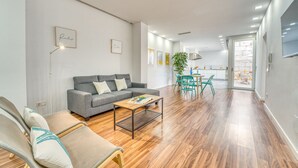 A modern living room with a grey sofa, a coffee table, and a dining area with a table and chairs. - Modern house Menut in Sa Pobla with jacuzzi (Sa Pobla)