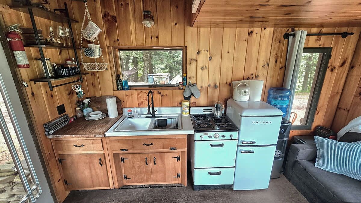 A compact kitchen with wooden cabinets, a sink, a stove, and a refrigerator.